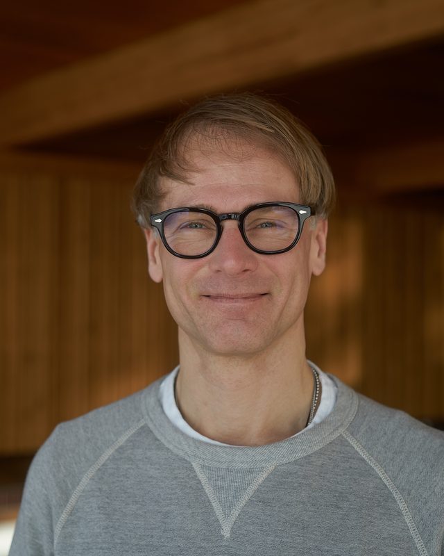 Smiling man in glasses in a warm wooden interior
